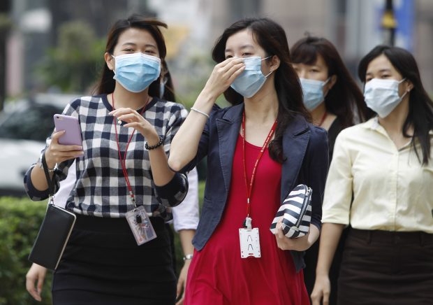 Malaysian women wear masks due to the haze in Kuala Lumpur, Malaysia Tuesday, Sept. 15, 2015. A layer of heavy haze has forced Malaysian authorities to shut schools in four states, including Kuala Lumpur, with officials to begin cloud seeding operations to try to induce rain to help clear the air. (AP Photo/Joshua Paul)