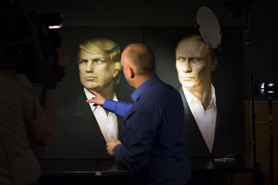 FILE - In this Wednesday, Nov. 9, 2016, file photo, a journalist points at a portrait of U.S. President-elect Donald Trump, with a portrait of Russian President Vladimir Putin during a live telecast of the U.S. presidential election in the Union Jack pub in Moscow, Russia. Putin's spokesman Peskov said Thursday that one way Trump could help build confidence with Russia after he becomes president would be to persuade NATO to slow down its expansion or withdraw its forces from Russia's borders. (AP Photo/Alexander Zemlianichenko, File)